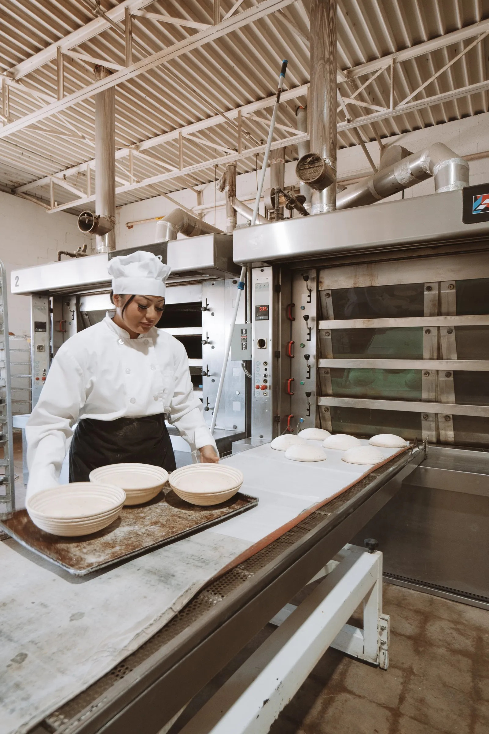 A baker loading the deck oven at the bakehouse