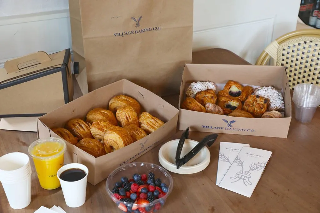 A catering spread: pastry boxes, coffee, orange juice and berries